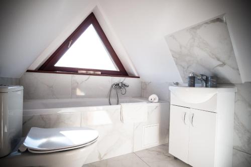a bathroom with a white toilet and a window at Apartamenty Tetmajera APARTZAKOP in Zakopane