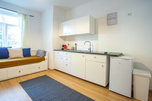 uma cozinha com armários brancos, um banco e um lavatório em FULL HOUSE Premium Apartments - Halle Südstadt em Halle an der Saale