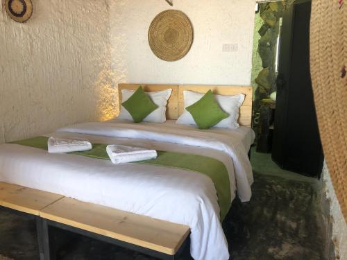 two beds with green and white pillows in a room at SAMA Al Khutaim-Heritage Home in Nizwa