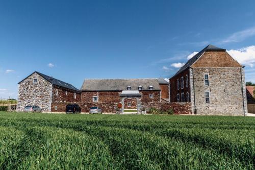 a large brick building with a grass field in front of it at Domaine Sur Les Sarts in Ohey