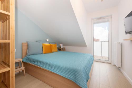 a bedroom with a bed with blue and orange pillows at JANTAR APARTAMENTY Posesja Kapitańska20A-28 in Grzybowo