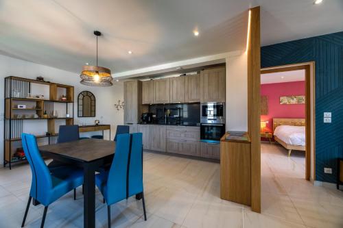 a kitchen and dining room with a table and blue chairs at Casa Nostra : bienvenue chez nous ! in Saint-Florent