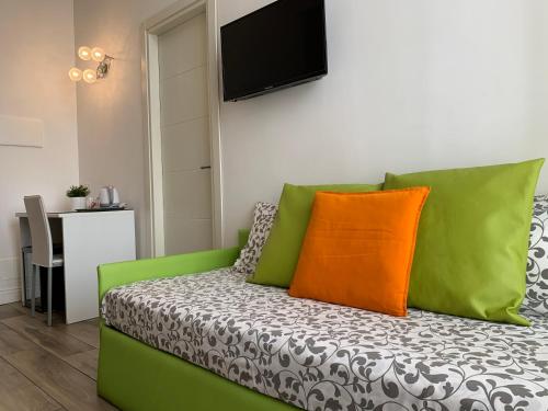 un sofá verde con almohadas de color naranja y verde en una habitación en B&B Casa Caracciolo, en Nápoles