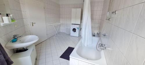 a bathroom with a tub and a sink and a washing machine at Cozy 2 room flat with WLAN in Magdeburg