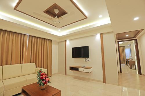 a living room with a couch and a tv at Krishnavalsam Regency in Guruvāyūr