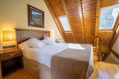 ein Schlafzimmer mit einem weißen Bett in einem Zimmer mit Fenstern in der Unterkunft Hotel & Restaurante Peña in Arrós