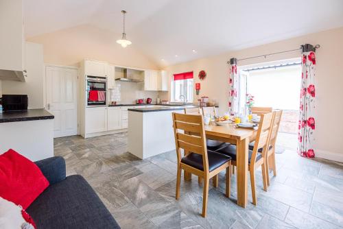 a kitchen and dining room with a table and chairs at Grove Farm Bungalow with swimming pool, Dallinghoo in Woodbridge
