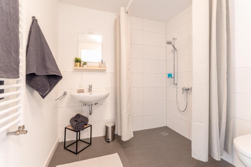 uma casa de banho branca com um lavatório e um chuveiro em NEU☆Business Apartment☆Messe/Airport☆Tiefgarage em Leinfelden-Echterdingen