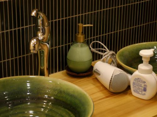 a bathroom counter with a green sink and a faucet at Gion Ryokan Q-beh in Kyoto