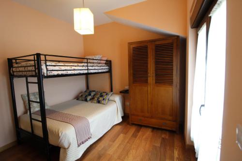 a bedroom with two bunk beds and a wooden floor at Apartamentos rurales la Aguilera in Oviñana
