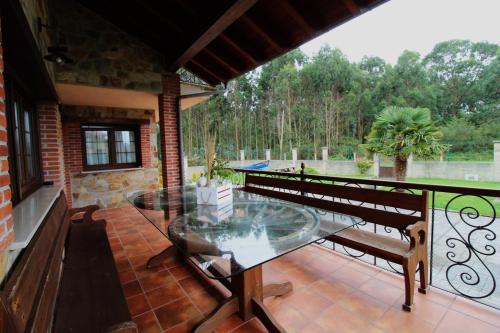 a balcony with a glass table and benches on it at Apartamentos rurales la Aguilera in Oviñana