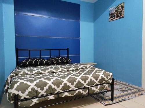 um quarto com uma cama com uma parede azul em LEBOK HOMESTAY AIRPORT KUANTAN em Kuantan
