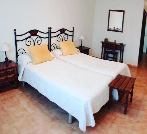 una camera da letto con un grande letto bianco con cuscini arancioni di HOTEL AS MACEIRAS a Trives