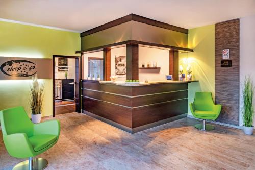 バート・ヘルスフェルトにあるHotel sleep & goの緑の椅子2脚が備わるレストランのバー