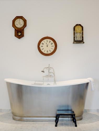 a bath tub with two clocks on the wall at The Vagabond's House Boutique Inn in Carmel