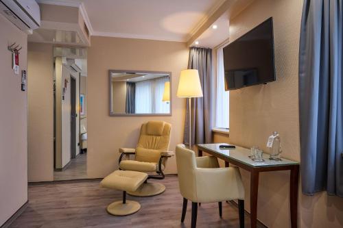 a hotel room with a table and chairs and a television at Cityhotel Kaiser Karl Aachen in Aachen