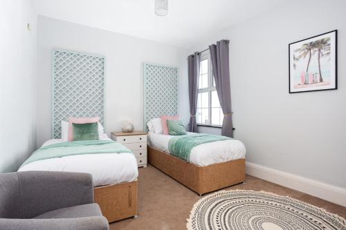 two beds in a room with a chair and a couch at Compass Point by Sorted Stay in Southend-on-Sea