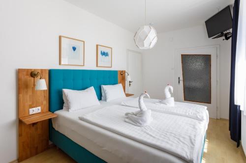 two swans sitting on a bed in a bedroom at Pension Laubenhof in Mörbisch am See