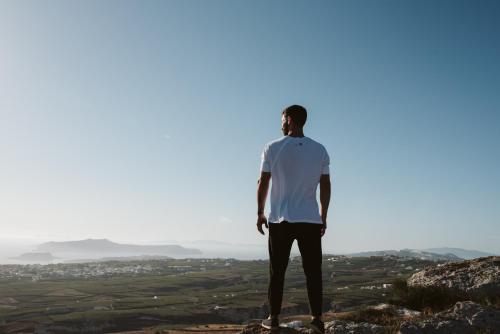a man standing on top of a mountain looking at the valley at Santorini Sky, The Lodge in Pirgos