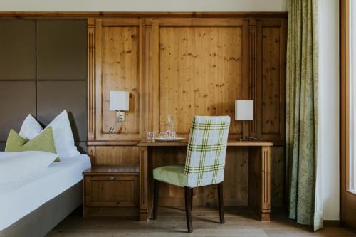 a bedroom with a bed and a desk with a chair at Hotel Tauernhof in Grossarl