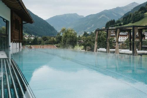 a large swimming pool with mountains in the background at Hotel Tauernhof in Grossarl