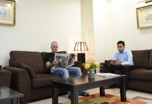 two men sitting on couches in a living room at Puteri Bay Hotel in Melaka