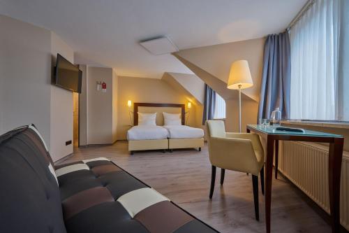 Pokój hotelowy z łóżkiem i biurkiem w obiekcie Cityhotel Kaiser Karl Aachen w Akwizgranie