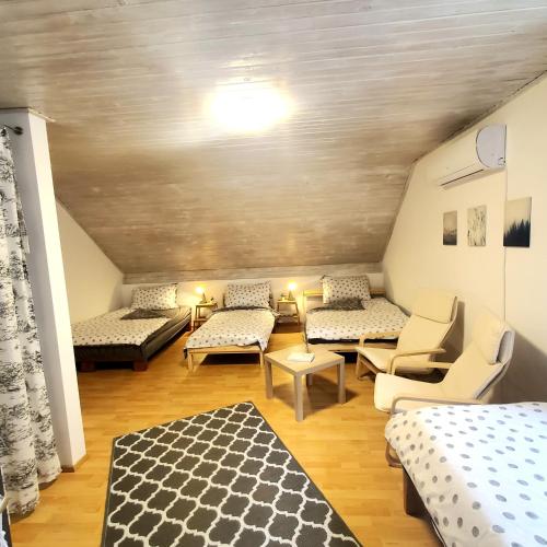 a attic room with three beds and a couch at Duna House Duna Ház in Tass