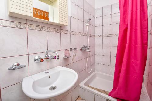 un bagno con lavandino e tenda doccia rosa di Apartments Jakoubek a Podglavica