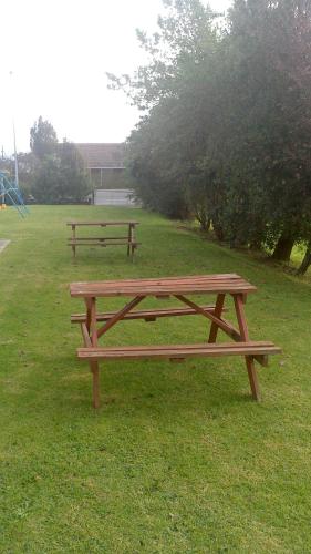 two wooden benches sitting in the grass in a park at Otaki Motel in Otaki