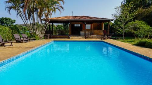 a swimming pool with chairs and a gazebo at Pousada Recanto Por do Sol in Morungaba