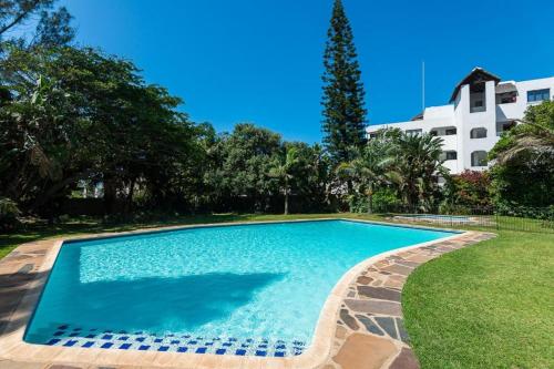 a swimming pool in a yard with a building in the background at Seabreeze At 301 in Ballito