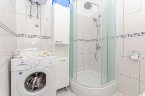 a washing machine in a bathroom with a shower at Apartments Jerko in Sutivan