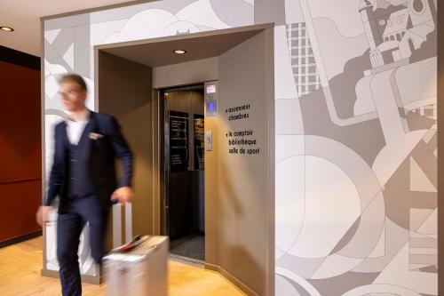 a man in a suit walking through a elevator at Hotel La Diligence in Obernai