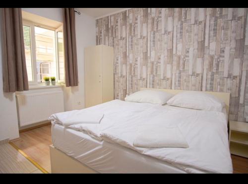 a white bed in a bedroom with a wall at Easy Star Hotel in Budapest