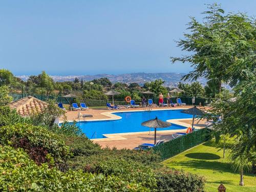 una gran piscina con sillas y sombrillas en Apartment in La Mairena, en Mijas Costa