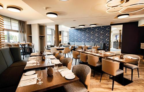a dining room with wooden tables and chairs at Median Hotel Hannover Lehrte in Lehrte