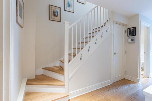 a white staircase in a home with wooden floors at Stylish Mews house with parking in London