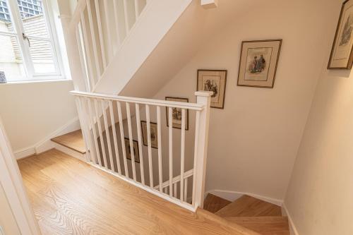 a staircase with white railings and pictures on the wall at Stylish Mews house with parking in London