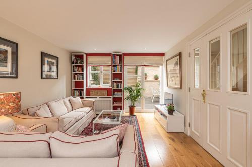 a living room with two couches and a book shelf at Stylish Mews house with parking in London