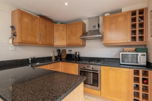a kitchen with wooden cabinets and a counter top at Stylish Mews house with parking in London
