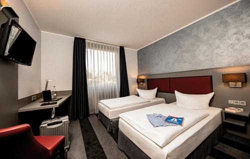 レールテにあるメディアン ホテル ハノーバー レールテのベッド2台とテレビが備わるホテルルームです。