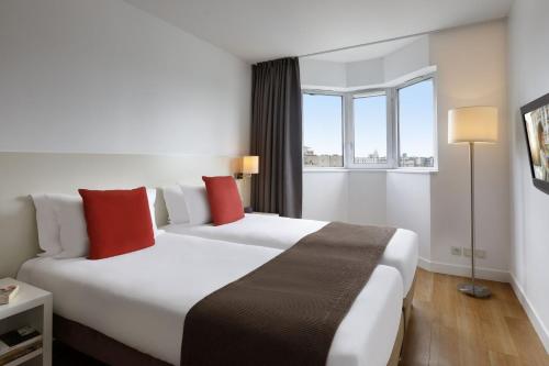 una camera d'albergo con due letti e una finestra di Citadines Montparnasse Paris a Parigi