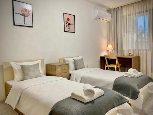 a hotel room with two beds and a desk at Spacious & Cozy 2 bed Apartment with Work Space & Fast Wi-fi in Stara Zagora