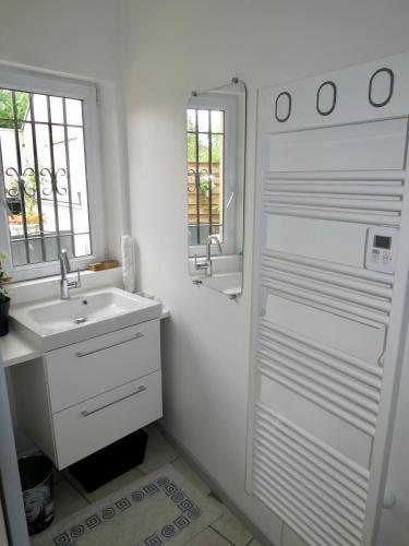 une salle de bain blanche avec un lavabo et une fenêtre dans l'établissement Duplex contemporain terrasse extérieure parking, à Lèves
