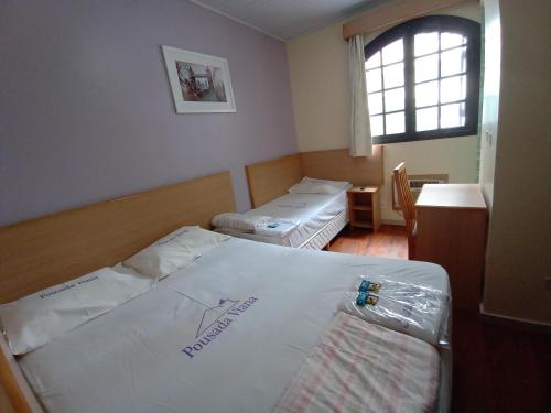 een kleine kamer met 2 bedden en een raam bij Hotel Pousada Viana in Sao Paulo