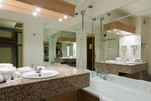 een badkamer met een wastafel, een bad en een spiegel bij Comfort Hotel Toulouse Sud in Ramonville-Saint-Agne