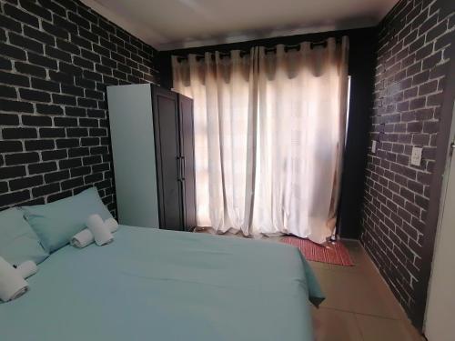 um quarto com uma cama branca e uma parede de tijolos em Mels em Richards Bay