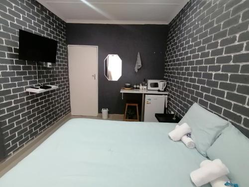 um quarto com uma cama branca e uma parede de tijolos em Mels em Richards Bay