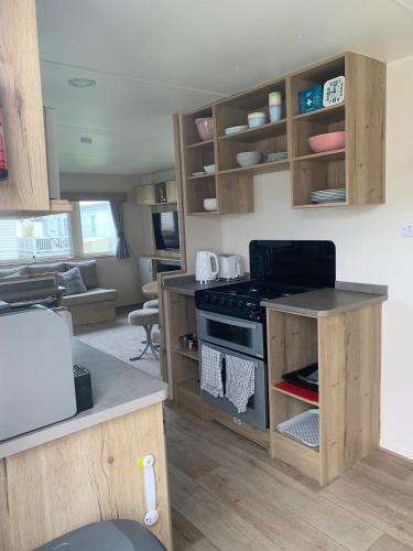 a kitchen with wooden cabinets and a stove top oven at Whitstable, DP42, 2 bed park home, Alberta Holiday Park in Whitstable